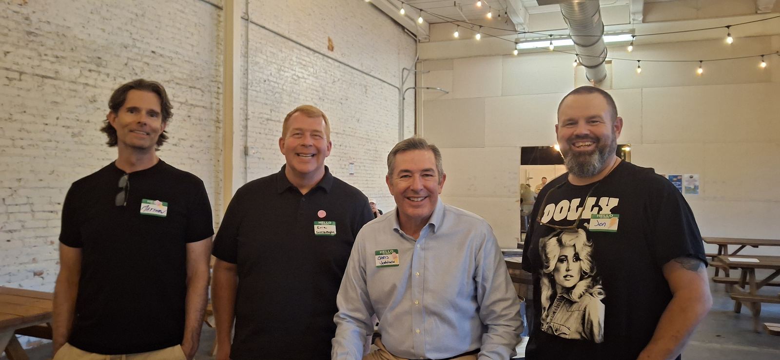 Four attendees wearing name tags, standing together and smiling.